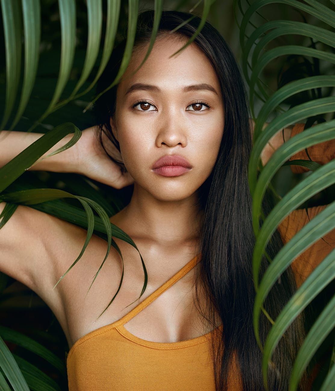 woman posing begind tropical leaves