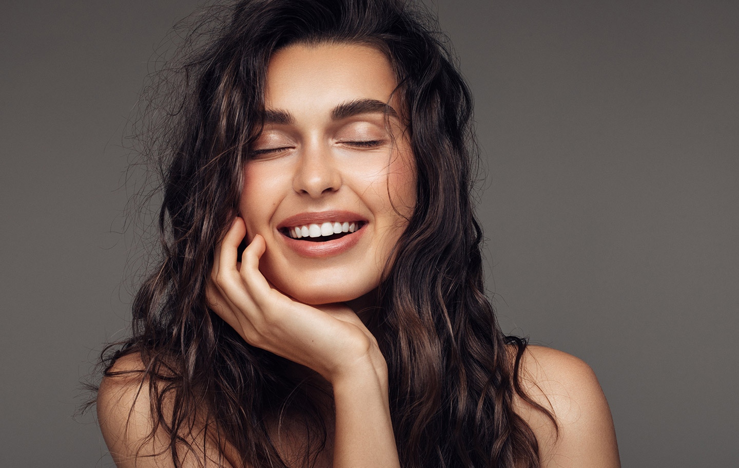 brunette woman with closed eyes smiling