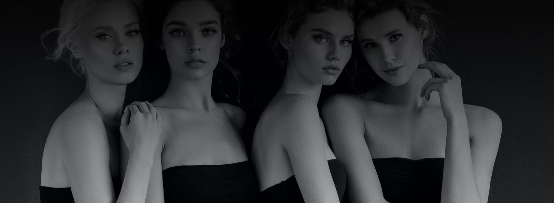 Four women wearing black dresses posing.